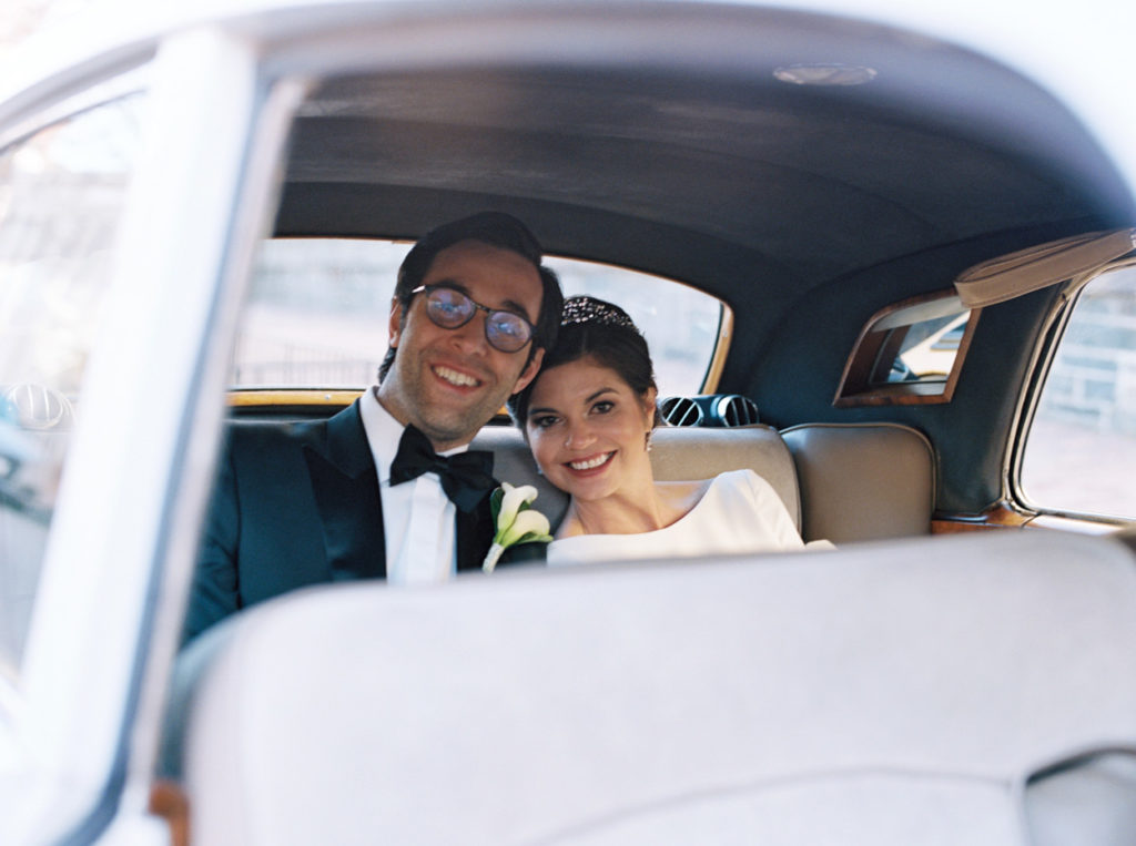 Bride and groom pose for photo inside vintage Rolls Royce car