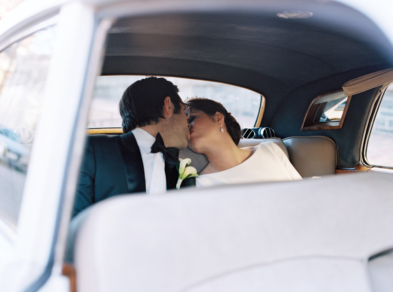 Wedding couple kisses inside vintage Rolls Royce
