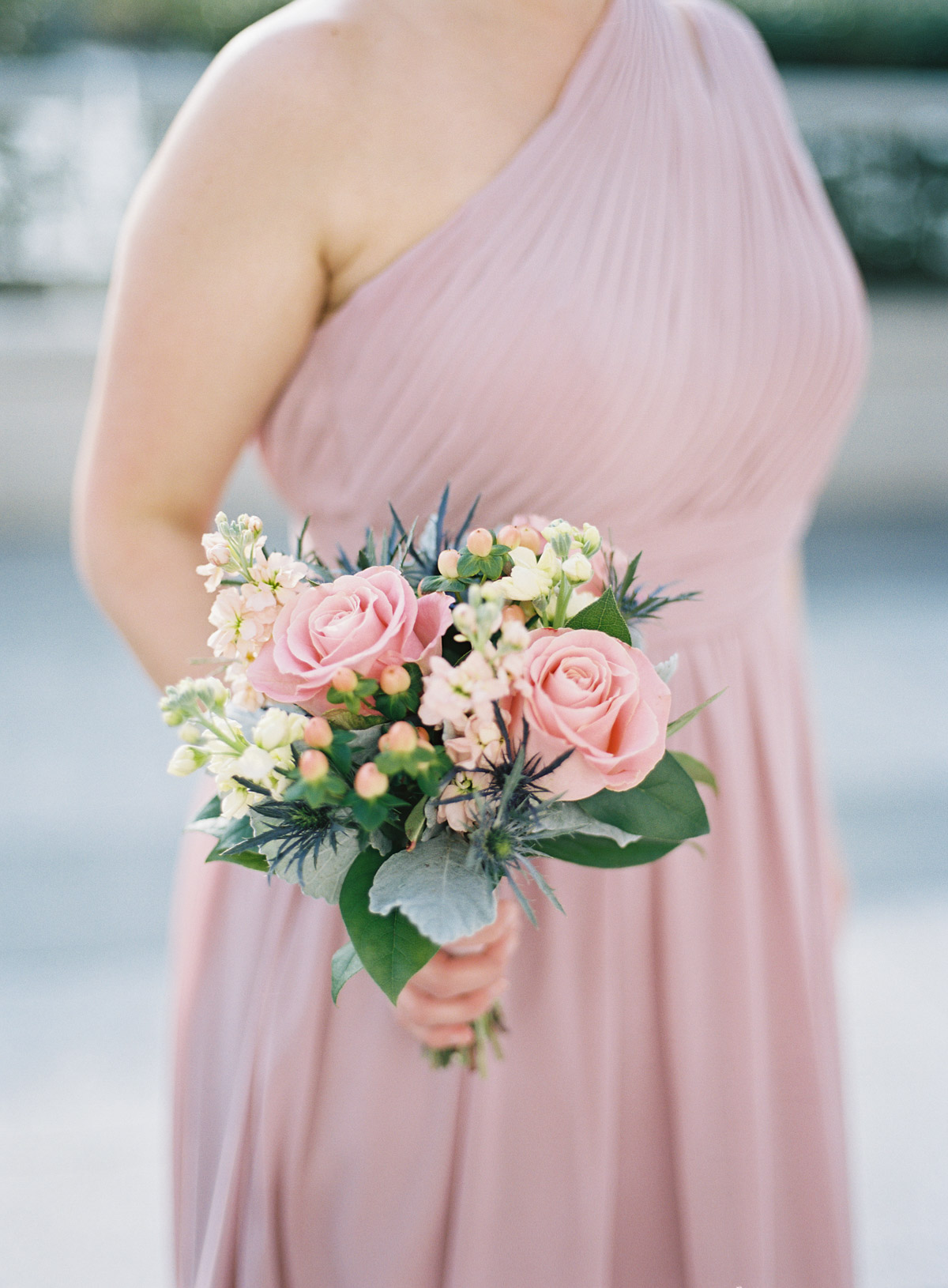 Bridesmaid wearing pink one-shoulder dress posing for photo