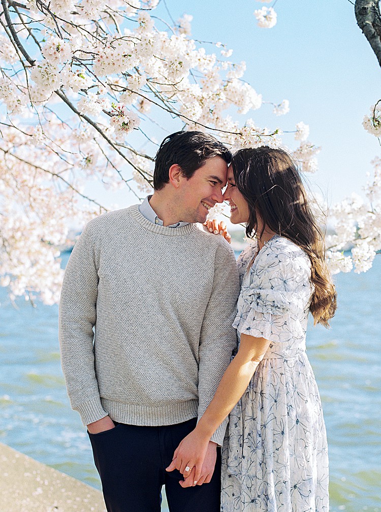 Couple poses for engagement photos at the cherry blossoms on the Tidal Basin in Washington, D.C.