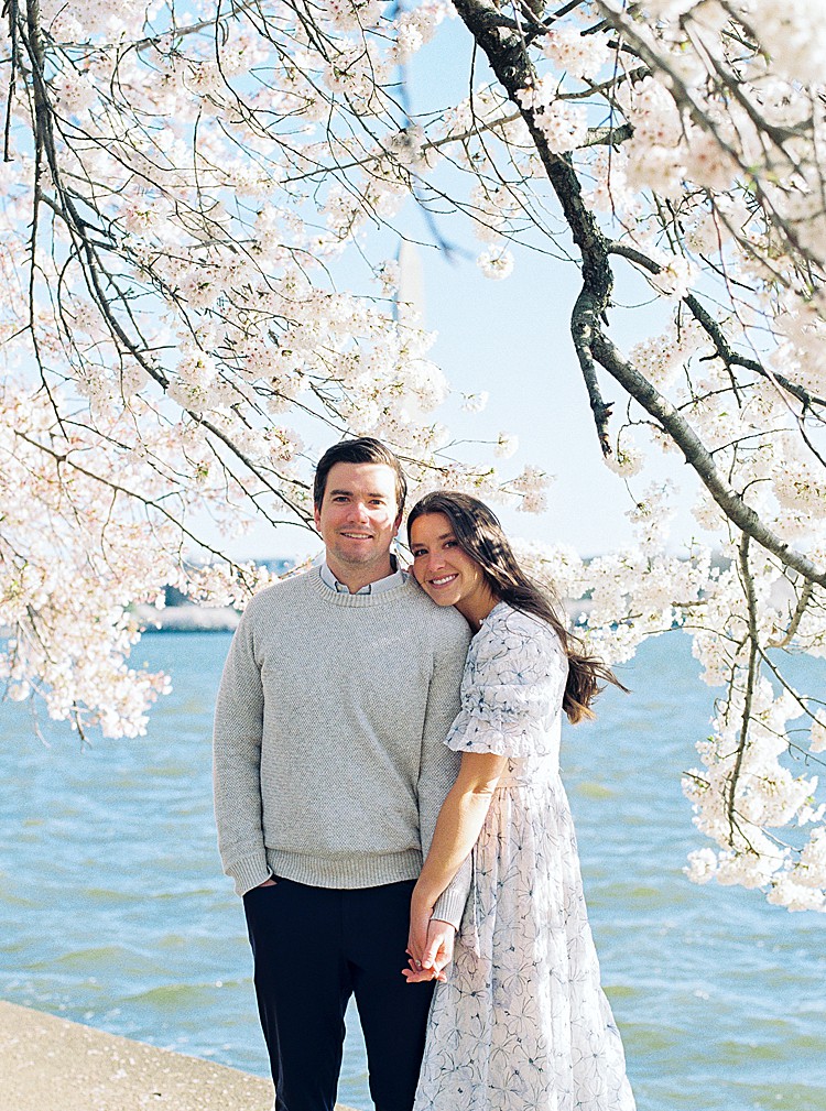 Couple poses for engagement photos at the cherry blossoms on the Tidal Basin in Washington, D.C.